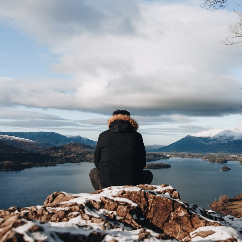 man meditating on a rock