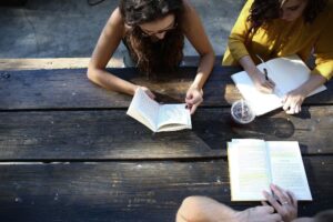 women writing in notebooks on bench